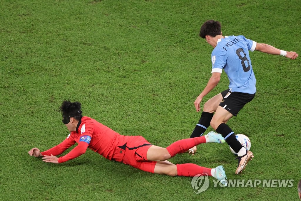 Son Heung-min of South Korea (L) falls after a challenge from Facundo Pellistri of Uruguay during the countries' Group H match at the FIFA World Cup at Education City Stadium in Al Rayyan, west of Doha, on Nov. 24, 2022. (Yonhap)