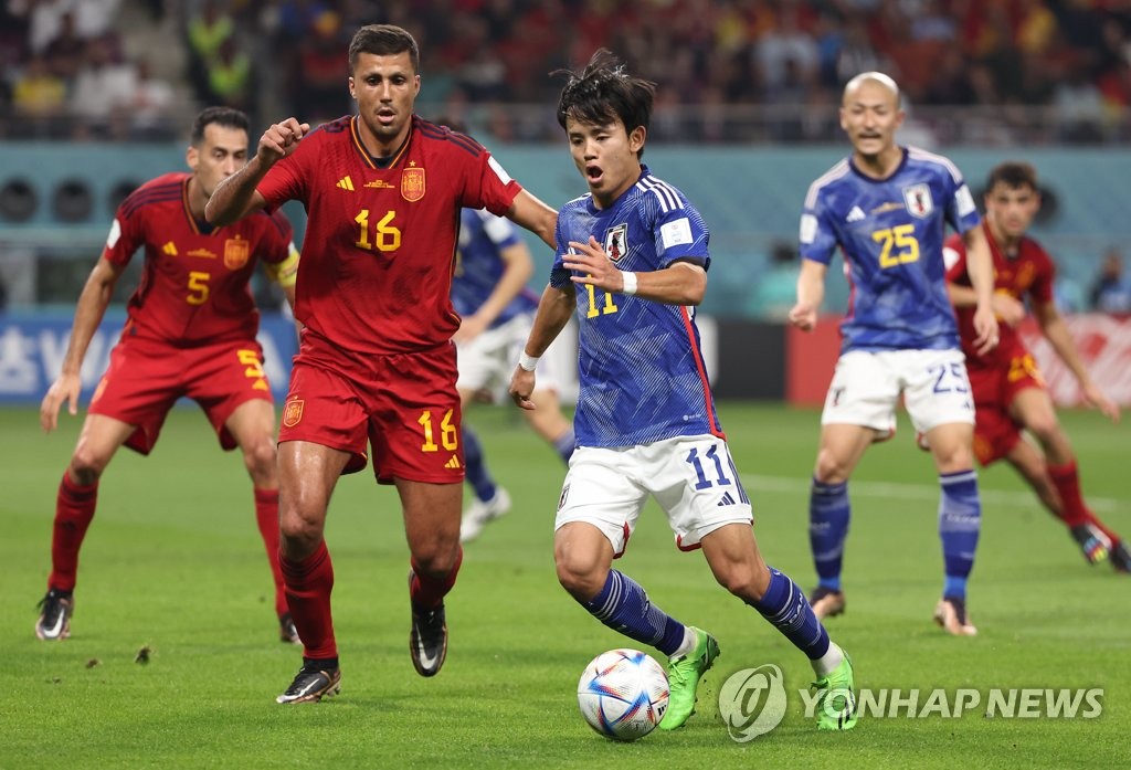 Takefusa Kubo of Japan (R) tries to dribble past Rodri of Spain during the countries' Group E match at the FIFA World Cup at Khalifa International Stadium in Al Rayyan, west of Doha, on Dec. 1, 2022. (Yonhap)