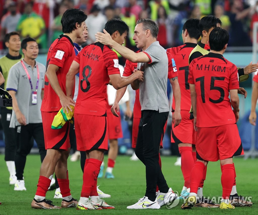 South Korea head coach Paulo Bento (C) consoles his players after their 4-1 loss to Brazil in the round of 16 at the FIFA World Cup at Stadium 974 in Doha on Dec. 5, 2022. (Yonhap)