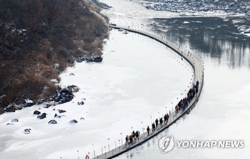 Hikers walk on a floating bridge across the frozen Hantan River in Cheolwon County, Gangwon Province, on Jan. 19, 2023. (Yonhap)