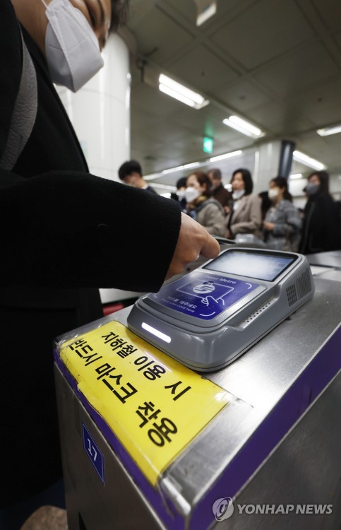 A passenger wearing a facial mask touches a transportation card to the card reader on a turnstile at a subway station in Seoul on March 15, 2023. The government said South Korea will end the mask mandate for public transportation next week, lifting one of the last-remaining COVID-19 restrictions amid a stable virus situation. (Yonhap)
