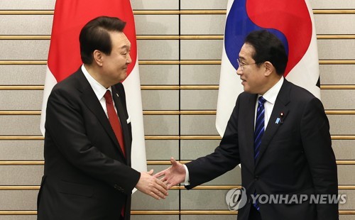 握手を交わす尹大統領（左）と岸田首相＝１６日、東京（聯合ニュース）