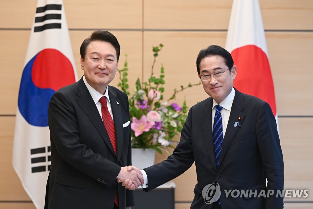 握手を交わす尹大統領（左）と岸田首相＝１６日、東京（聯合ニュース）