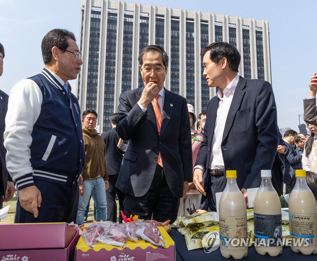 Prime Minister Han Duck-soo (C), alongside South Jeolla Gov. Kim Yung-rok (L), eats bread made from potatoes cultivated in Haenam, a town 334 kilometers south of Seoul, in the southwestern province of South Jeolla, as he attends a publicity event in Seoul on March 22, 2023, to promote visits to the province. (Yonhap)
