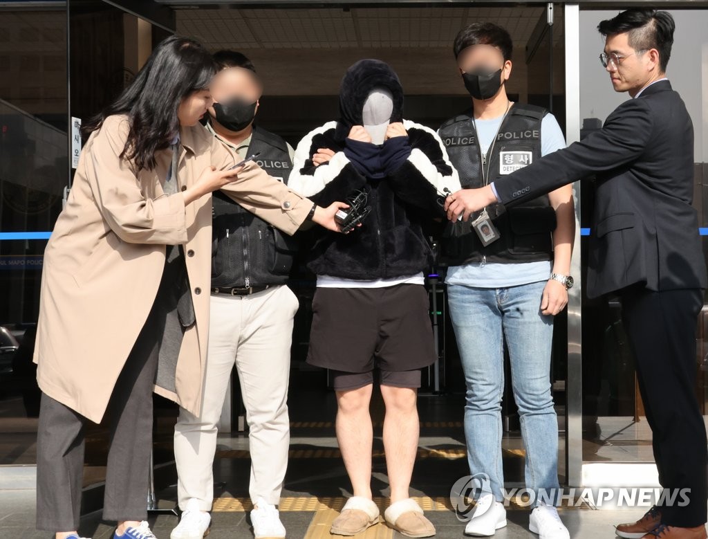 A man surnamed Gil (C), a suspect in a drug scam targeting students, is being transferred from a police station in western Seoul on April 17, 2023. (Yonhap)