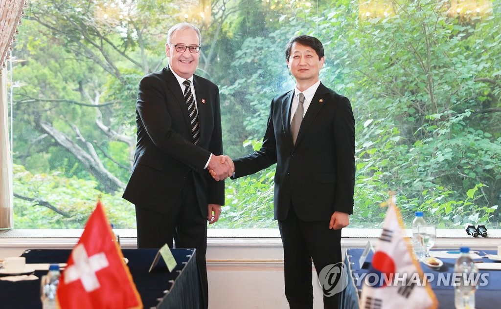 Le ministre du Commerce Ahn Duk-geun (à dr.) échange le jeudi 18 mai 2023 une poignée de main avec le conseiller fédéral suisse Guy Parmelin, à la tête du département fédéral de l'Economie, de la Formation et de la Recherche, dans un hôtel de Séoul. 