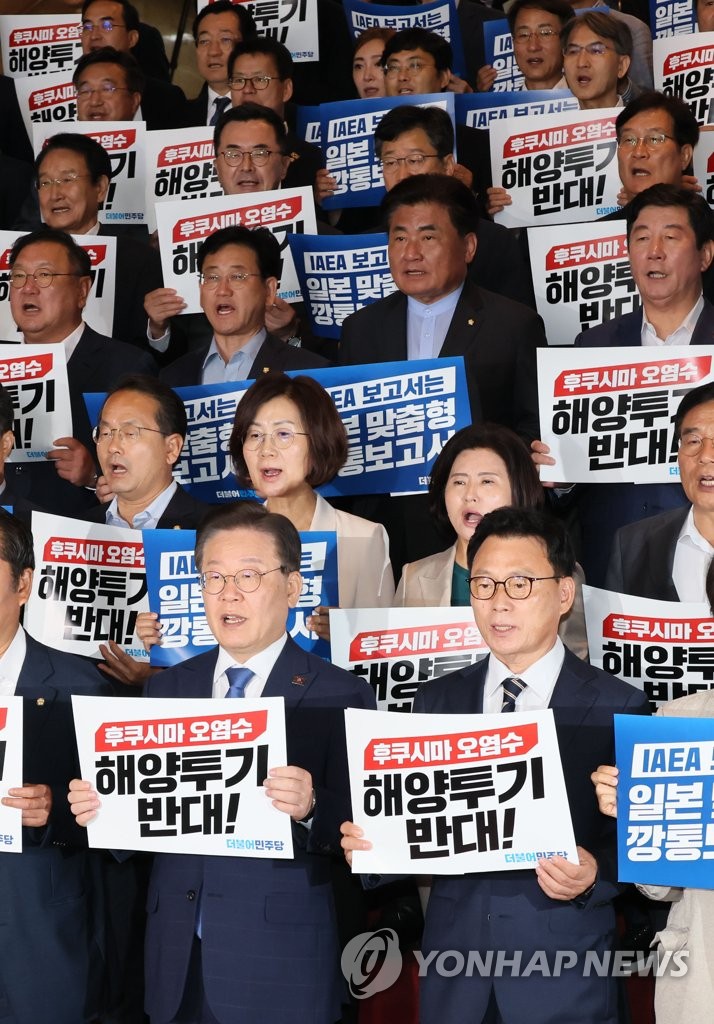 Lee Jae-myung (segunda de izquierda a derecha, primera fila), líder del principal Partido Democrático de la oposición, y otros legisladores del partido cantan eslóganes durante un mitin en la Asamblea Nacional en Seúl el 5 de julio de 2023, para expresar su objeción a la descarga planificada de Japón de agua radiactiva tratada de los reactores nucleares paralizados en Fukushima al océano.  El mitin se produjo un día después de que la Agencia Internacional de Energía Atómica presentara su conclusión de que el plan japonés es consistente con sus estándares de seguridad.  (Yonhap)