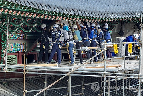Workers remove the signboard of Gwanghwamun gate in central Seoul on Oct. 12, 2023, ahead of the unveiling of a new signboard with golden letters on Oct. 15. (Yonhap)
