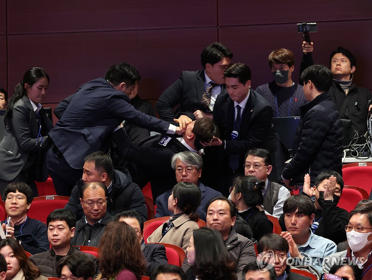 Rep. Kang Sung-hee (C) of the minor progressive Jinbo Party is carried by presidential security agents during a ceremony at the Sori Arts Center in Jeonju, 192 kilometers south of Seoul, on Jan. 18, 2024. (Yonhap)
