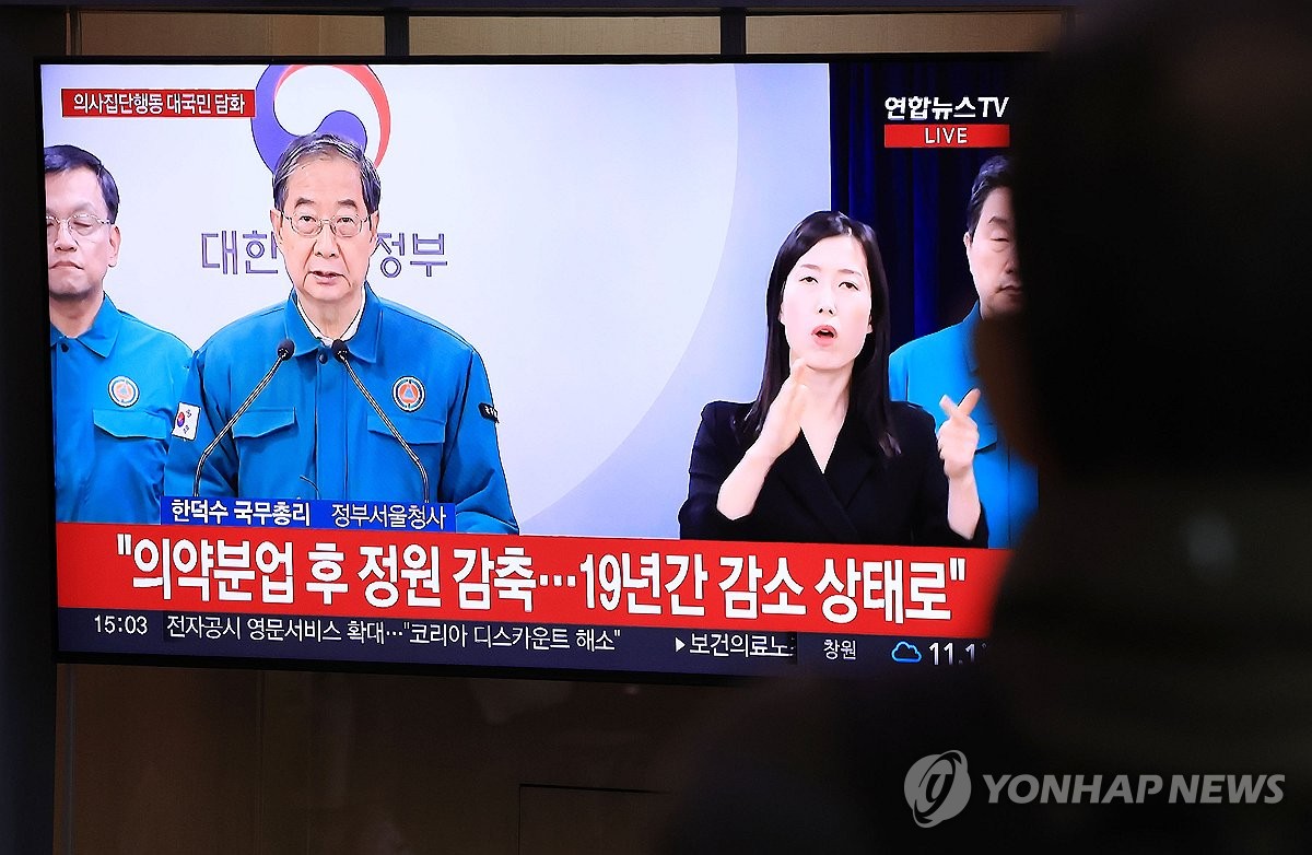 Los ciudadanos ven un informe de noticias sobre la declaración del primer ministro Han Duck-soo sobre el aumento de las cuotas de las escuelas de medicina en la estación de Seúl, en el centro de Seúl, el 18 de febrero de 2024. (Yonhap) 