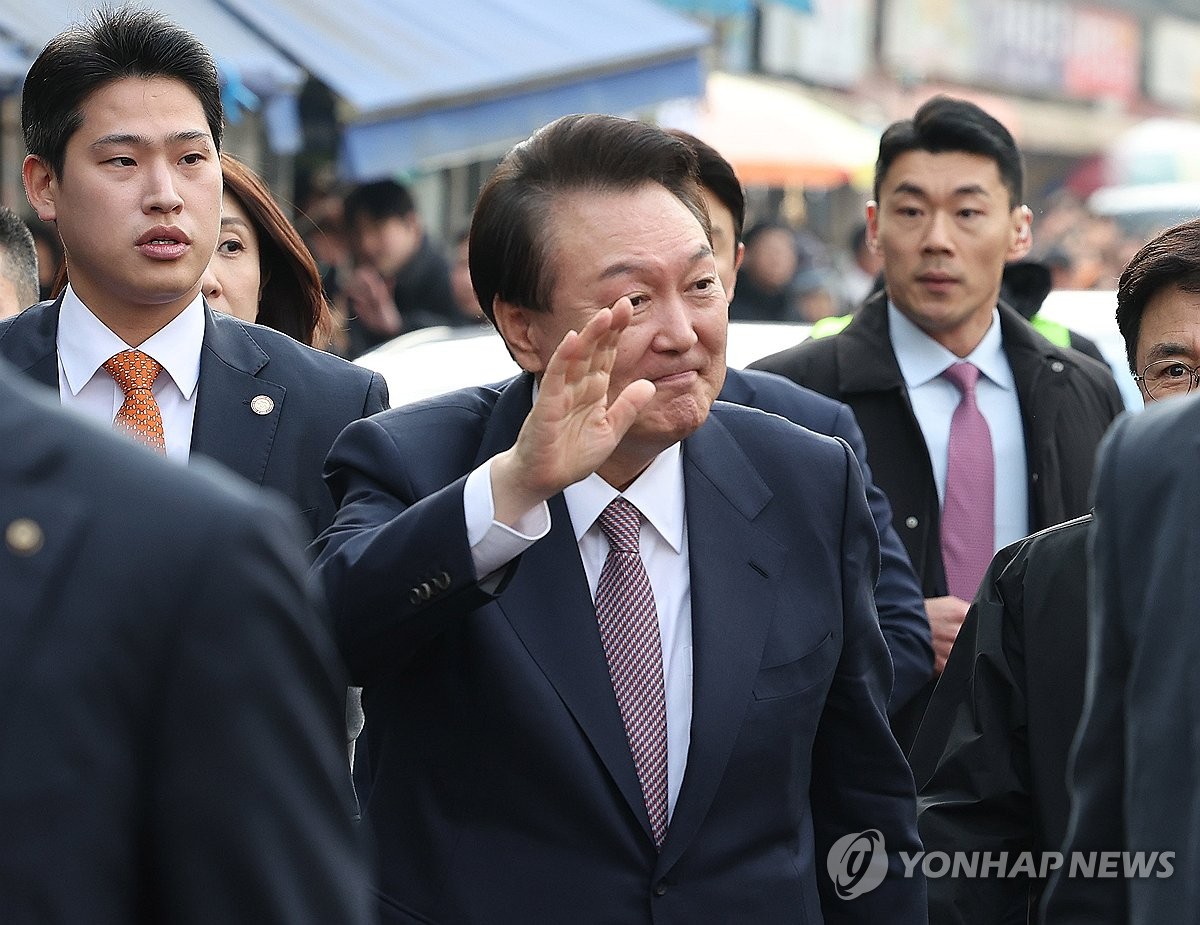 El presidente Yoon Suk Yeol (centro) saluda durante una visita a un mercado tradicional en Seosan, a 98 kilómetros al suroeste de Seúl, el 26 de febrero de 2024. (Foto de la piscina) (Yonhap)