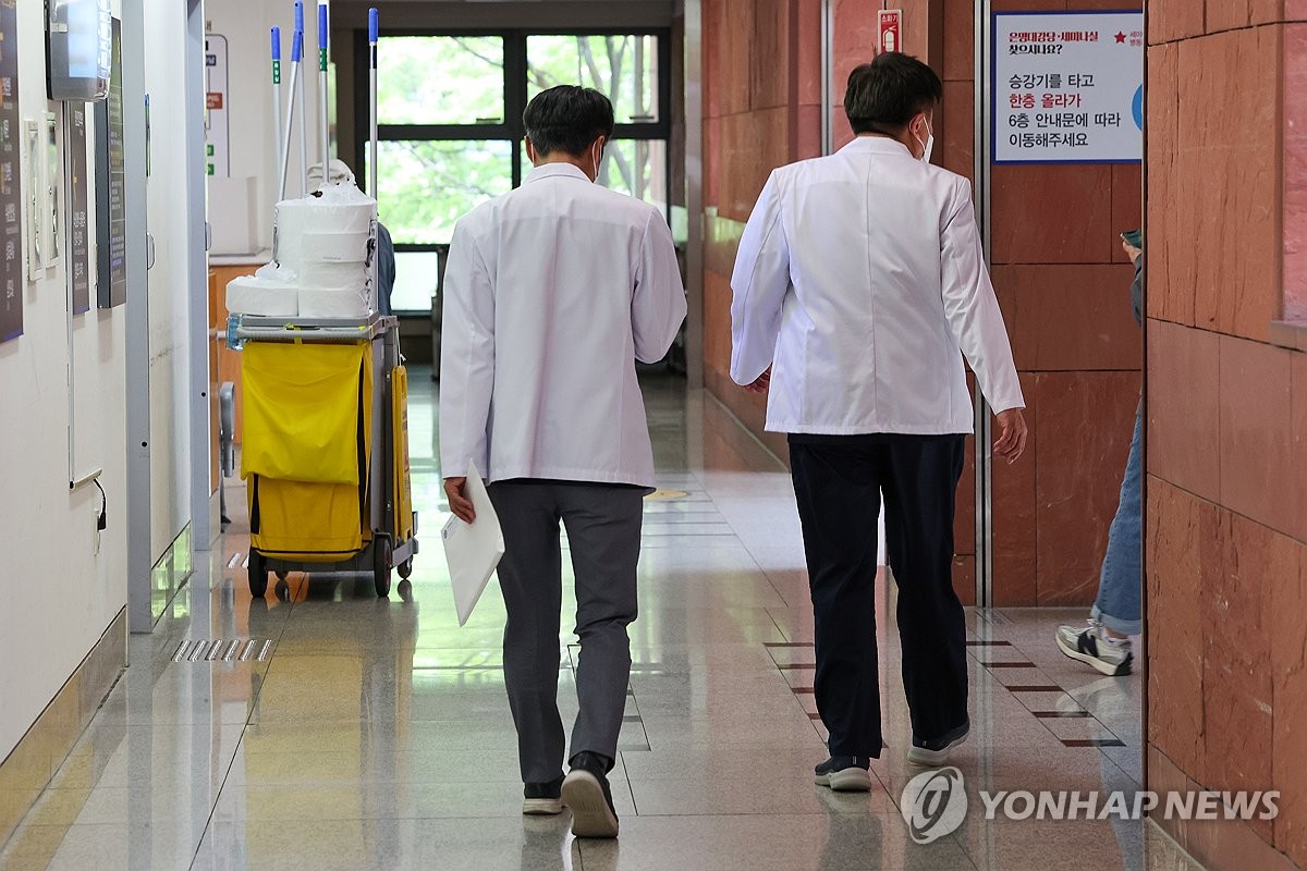 Doctors walk down a hallway at a university hospital in Seoul on April 29, 2024. Earlier in the day, five major hospitals in Seoul, including Seoul National University Hospital, decided to allow their doctors to have a day of rest each week starting this week due to their excessive workload amid a monthslong nationwide walkout by some 13,000 trainee doctors. (Yonhap)