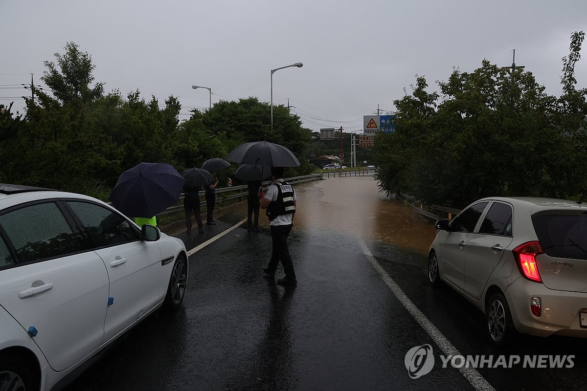 Agentes de policía impiden el paso de vehículos a una sección inundada de una carretera en Paju, provincia de Gyeonggi, el 17 de julio de 2024. (Yonhap) 