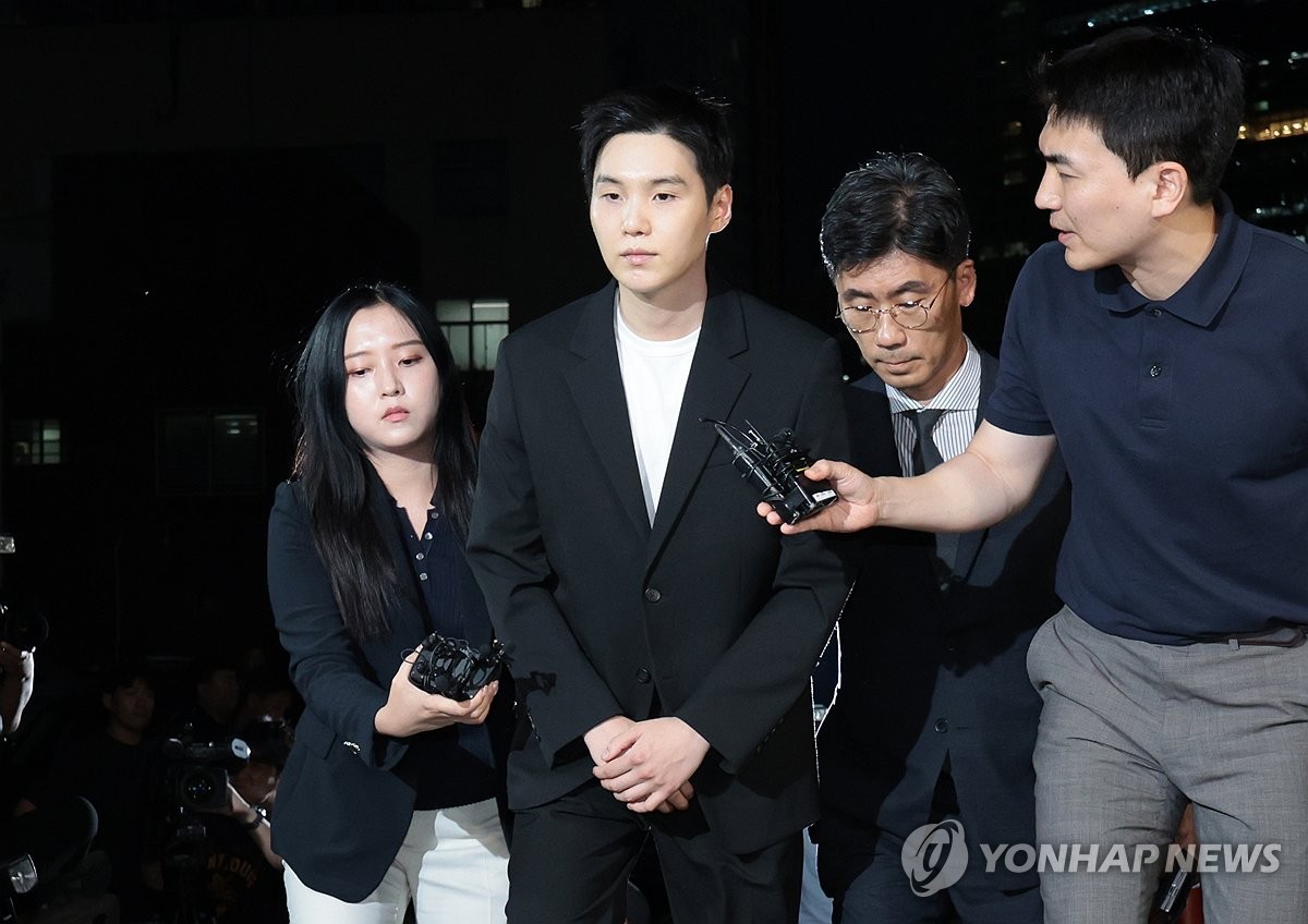 Suga (3º por la dcha.), miembro del supergrupo de K-pop BTS, llega a la Estación de Policía de Yongsan, en Seúl, el 23 de agosto de 2024, para someterse a un interrogatorio por su presunta conducción, en estado de ebriedad, de una motocicleta eléctrica, a principios de agosto.